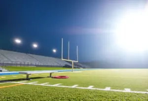 Empty football field at night with stadium lights